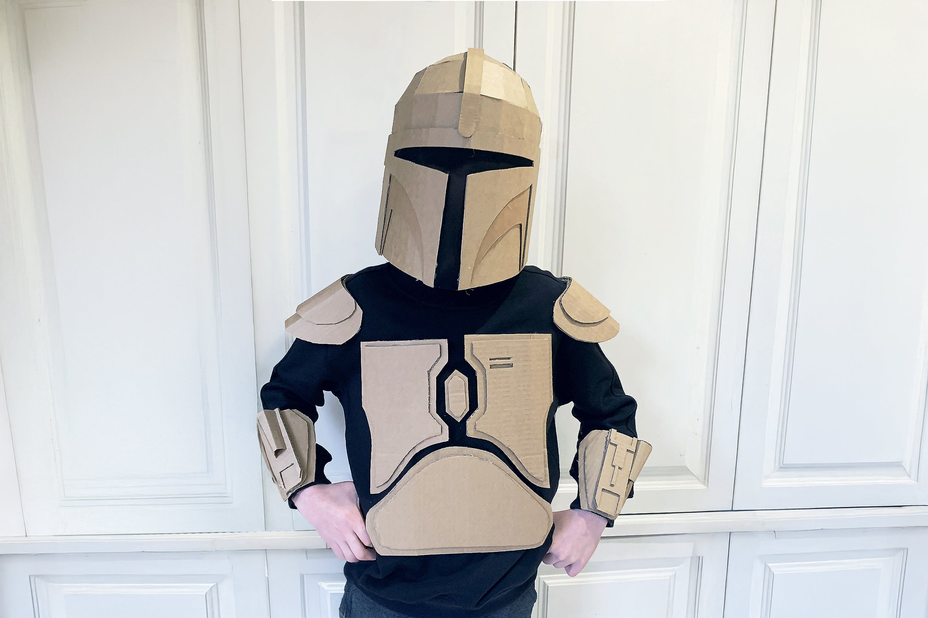Child wearing a costume made from a template. The child is inspired to wear a costume like a mandalorian with helmet and armour.