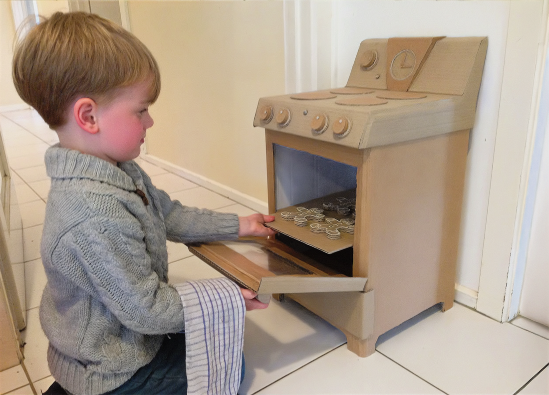 A Child playing with a toy oven made out of cardboard. 