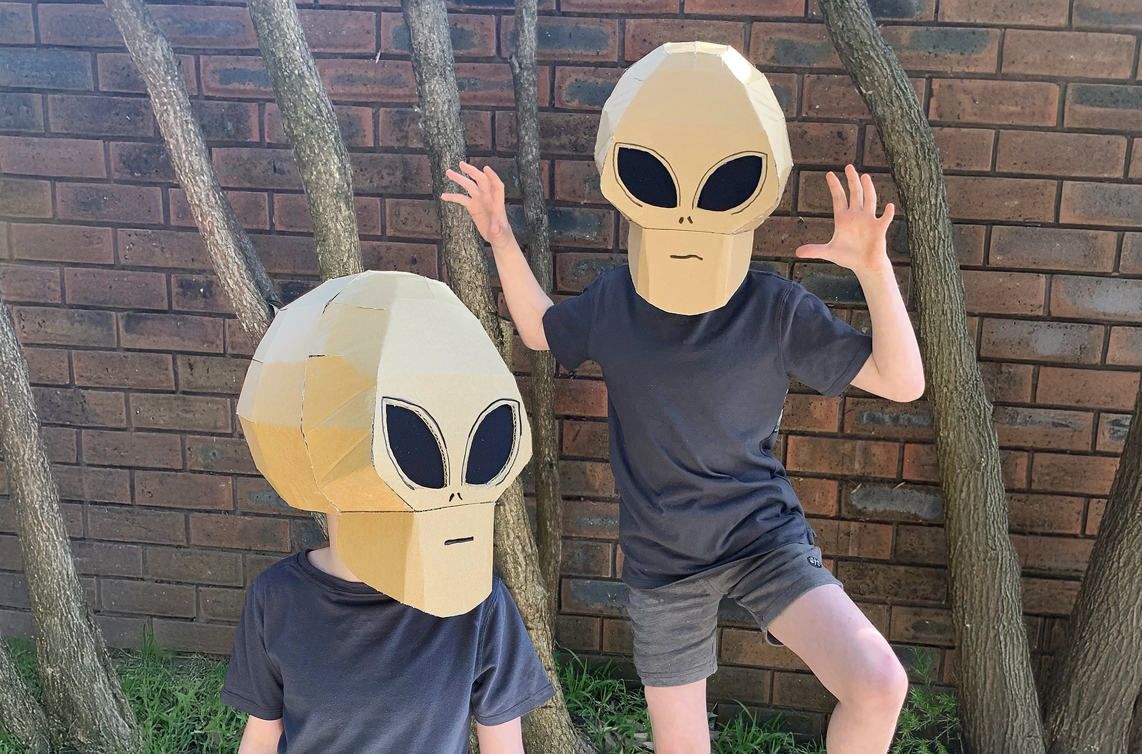 Two kids dressed as aliens in cardboard alien costumes.