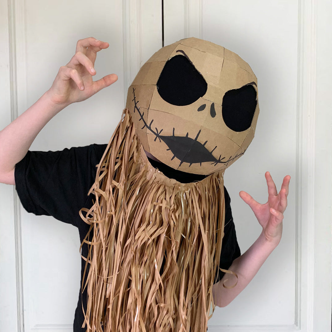 Person wearing a Cardboard Jack Skellington inspired mask with long hair against a white door background