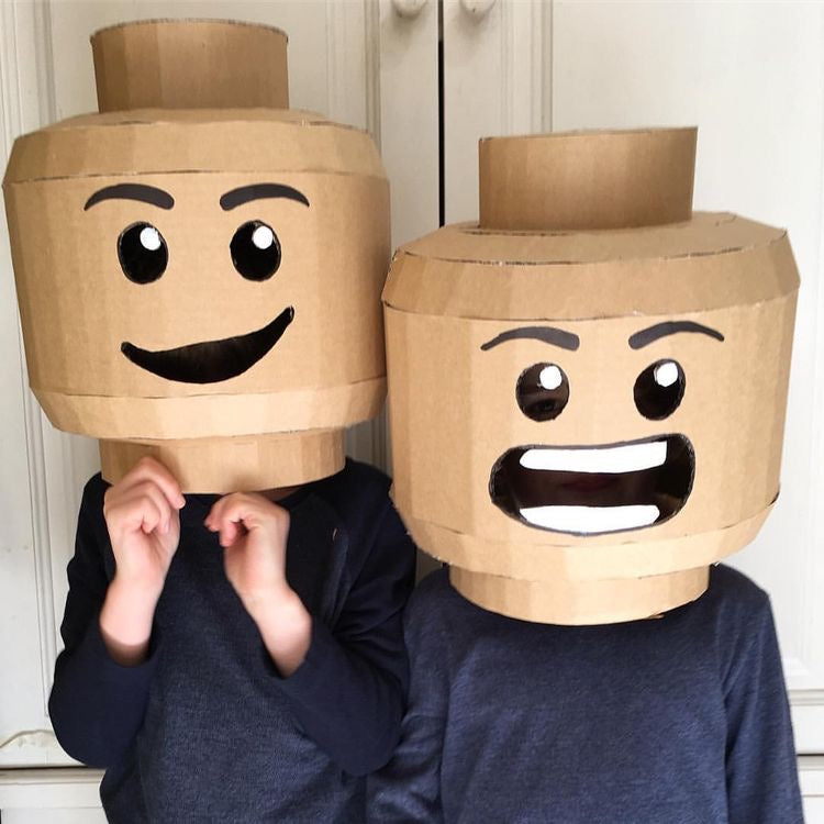 Two children wearing cardboard LEGO-like masks with expressive faces.
