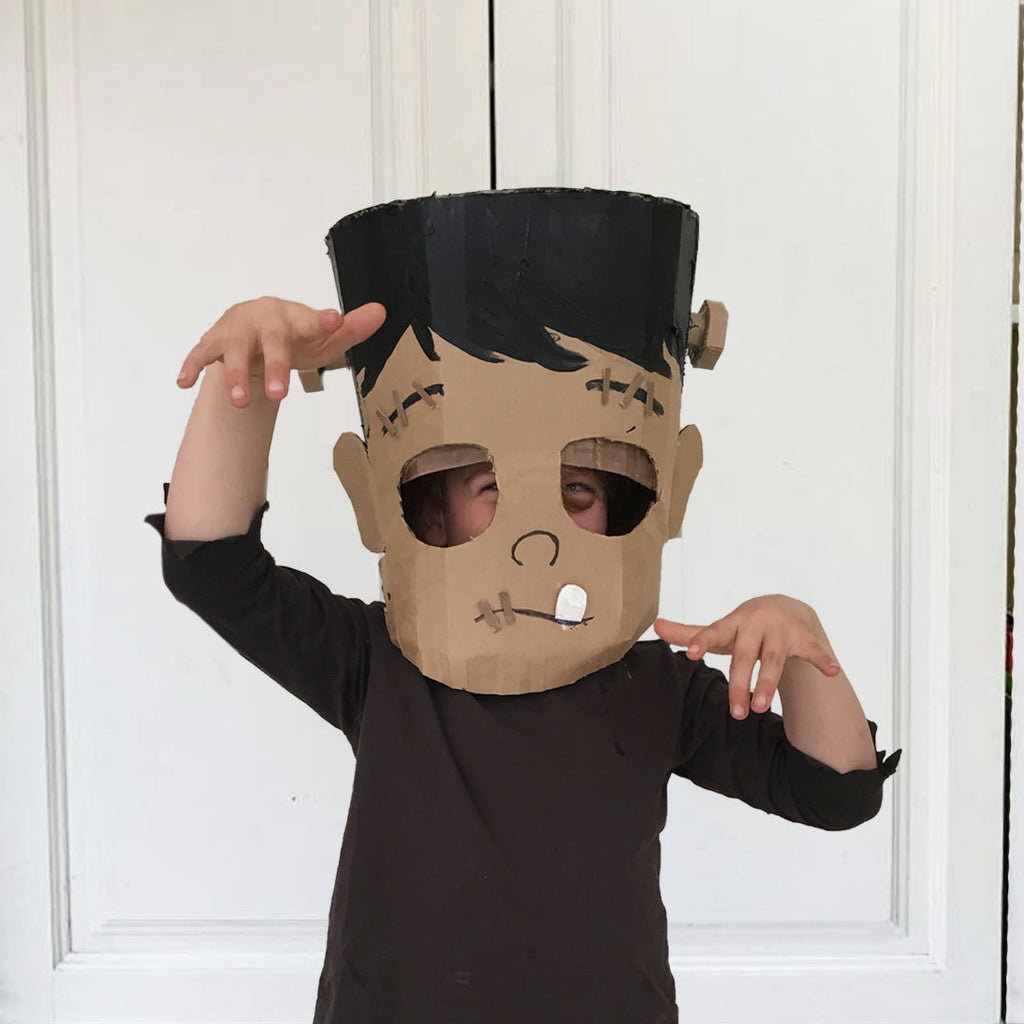 Child wearing a Cardboard Frankenstein monster mask against a white background