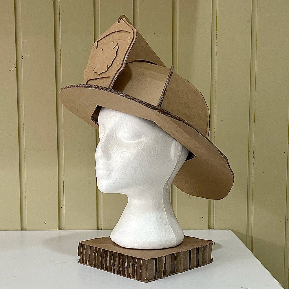 Cardboard helmet on a mannequin head against a green panelled wall