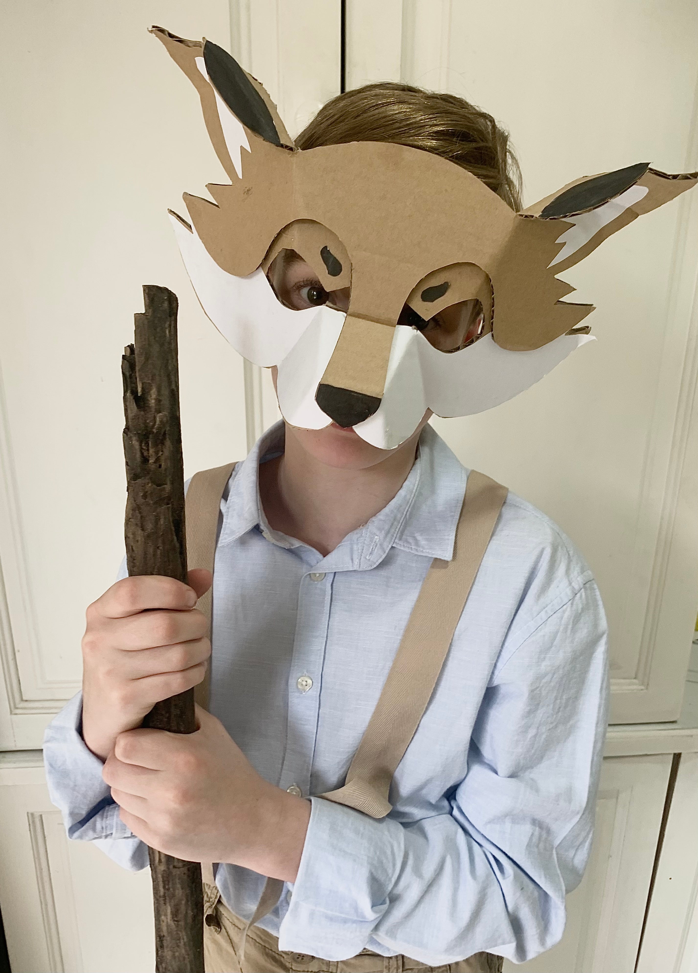 Person wearing a cardboard wolf mask holding a stick indoors dress up for bookweek as Mr Fox.