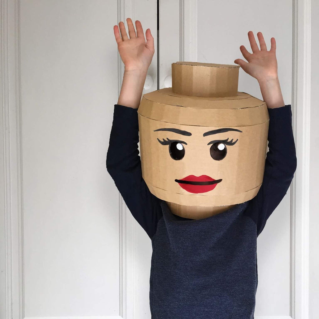A child wearing a cardboard brick head costume inspired by lego girl.
