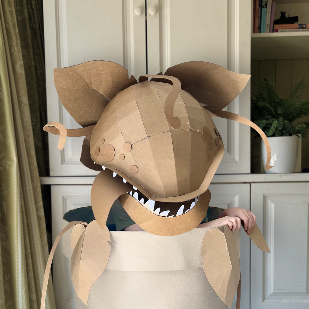 Cardboard costume of man eating plant inside a cardboard plant pot